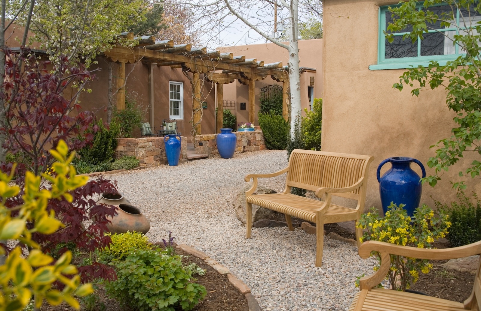 Discover The Best Museums In Santa Fe 2 The Gardens At El Farolito, A Santa Fe Bed And Breakfast, Featuring Plants, Blue Vases, And Benches.